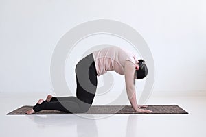 Woman doing yoga asana bitilasana cow or cat pose for gentle warm up for spine