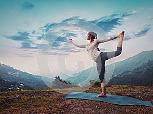 Woman doing yoga asana Natarajasana outdoors on sunset photo