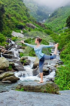 Woman doing yoga asana Natarajasana outdoors at waterfall