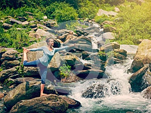 Woman doing yoga asana Natarajasana outdoors at waterfall