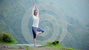 Woman doing yoga asana tree pose outdoors