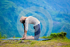 Woman doing yoga asana Ustrasana camel pose outdoors