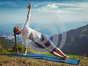 Woman doing yoga asana Vasisthasana - side plank pose outdoors