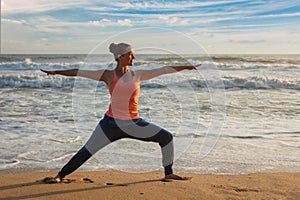 Woman doing yoga asana Virabhadrasana 1 Warrior Pose on beach on