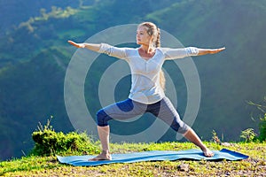 Woman doing yoga asana Virabhadrasana 2 - Warrior pose outdoors photo