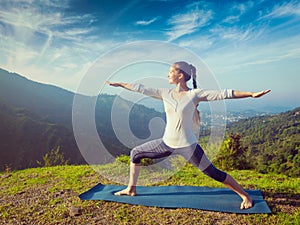 Woman doing yoga asana Virabhadrasana 2 - Warrior pose outdoors photo