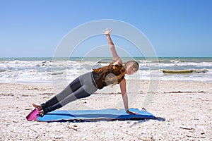 Woman doing yoga on beach in side plank
