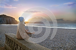 A woman doing yoga at the beach, at sunset time