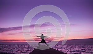 Woman doing yoga on the beach in surise