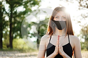 Woman doing yoga on the beach wearing a mask