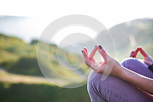woman doing yoga in beautiful nature background at sunset or sunrise, focus on hand - mindfulness and mental health and hygiene