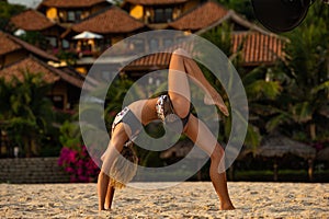 Woman doing yoga bridge pose on beach