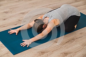 Woman doing yoga in child`s pose on mat