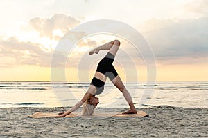 woman doing yoga downward facing dog pose on beach