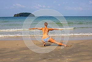 Woman doing yoga on empty beach. Tropical seaside vacation activity. Young girl in asana posture.