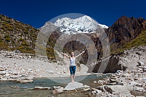 Woman is doing yoga excercises near big lake on the Manaslu circuit trak in Nepala