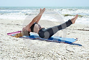 Woman doing yoga exercise on beach in fish