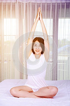 Woman doing yoga exercise on bed in bedroom