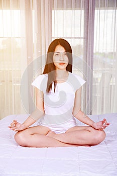 Woman doing yoga exercise on bed in bedroom