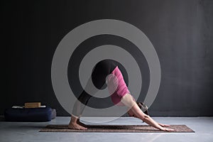 Woman doing yoga exercise downward facing dog pose, adho mukha svanasana