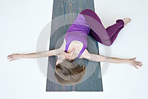 Woman doing yoga exercise on floor variation of Belly Twist Pose