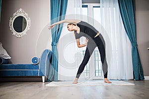 Woman doing yoga exercise at home. Morning workout in bedroom. Healthy and sport lifestyle.