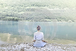 Woman doing yoga in front of a spectacular mountain lake