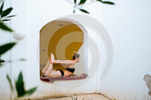 Woman doing yoga in the garden at the window