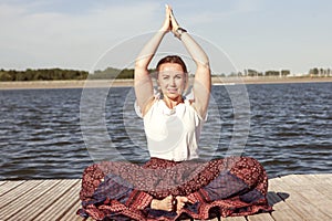 Woman doing yoga on the lake - relaxing in nature