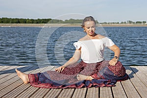 Woman doing yoga on the lake - relaxing in nature