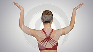 Woman doing yoga lotus pose with hands coupled on gradient background.