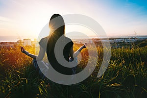 Woman doing yoga and meditates with beautiful view at sunset, sunrise. Easy pose