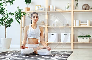 Woman doing yoga, meditating in Lotus position at home