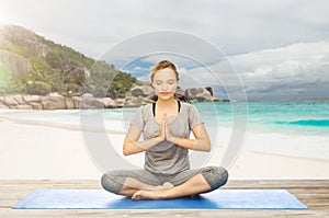 Woman doing yoga meditation in lotus pose on beach