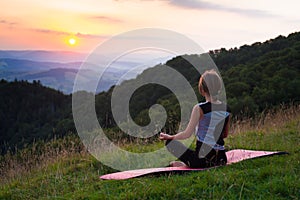 Woman doing yoga meditation in the mountains at dawn