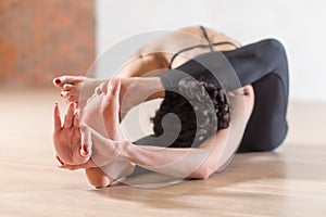 Woman doing yoga meditation and stretching exercise bending forward with her leg behind head