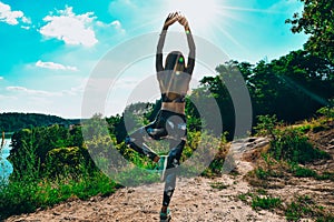Woman Doing Yoga On Mountain Against Sky and Sun. Hard light. Silhouette of girl doing outdoor sport stretch