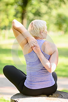 Woman doing yoga in nature, doing hand lock, Gomukasana. The concept of stretching, yoga.