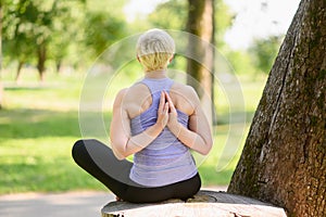 Woman doing yoga in nature doing reverse prayer, namaste behind her back.The concept of stretching, yoga.
