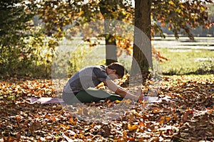 Woman doing yoga in the park in fall