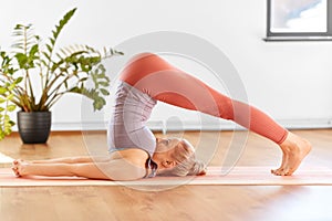 Woman doing yoga in plow pose at home