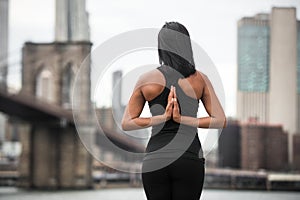 Woman doing yoga pose with arms on the back in New York City park. Yoga classes concept..