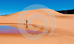 Woman doing yoga on sand dunes.