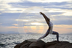 woman doing yoga on sea beach against beautiful sun rising sky