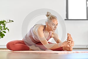 Woman doing yoga and seated forward bend at home