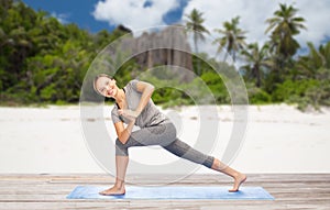 Woman doing yoga side angle pose on beach