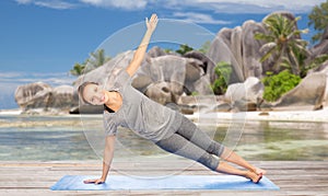 Woman doing yoga in side plank pose on beach