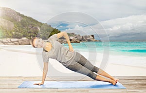 Woman doing yoga in side plank pose on beach