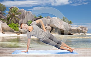 Woman doing yoga in side plank pose on beach