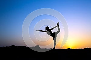 Woman doing yoga sunset silhouette